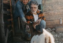 A happy retired couple enjoying life on their smallholding with a goat