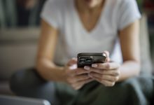 Person sitting indoors using a phone while resting on a sofa in a casual setting closeup