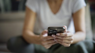 Person sitting indoors using a phone while resting on a sofa in a casual setting closeup