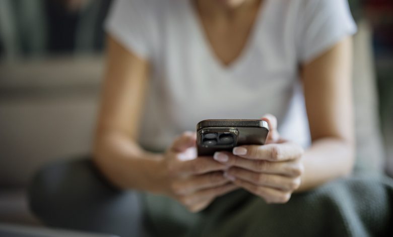 Person sitting indoors using a phone while resting on a sofa in a casual setting closeup